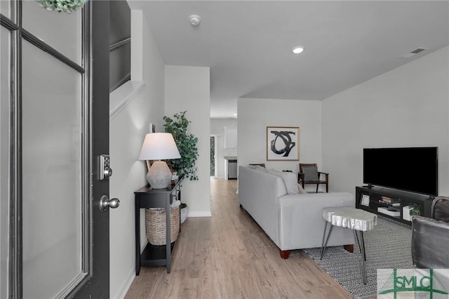 living room featuring visible vents, light wood-style flooring, and baseboards