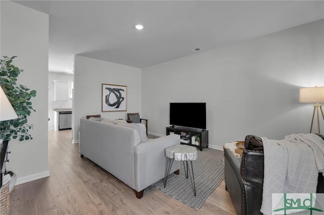 living room featuring light wood-style flooring, recessed lighting, and baseboards