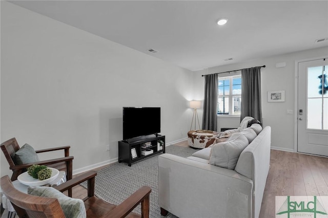 living area with visible vents, baseboards, and wood finished floors