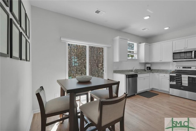 kitchen with light stone counters, white cabinetry, visible vents, and stainless steel appliances