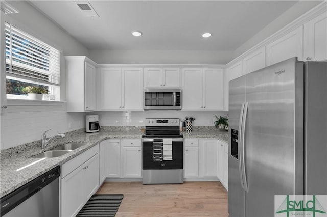 kitchen with a sink, light wood-type flooring, white cabinetry, light stone countertops, and stainless steel appliances