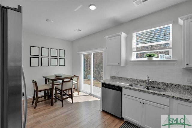kitchen with tasteful backsplash, white cabinetry, appliances with stainless steel finishes, light wood finished floors, and a sink