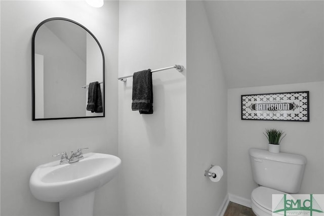 bathroom with baseboards, vaulted ceiling, a sink, and toilet