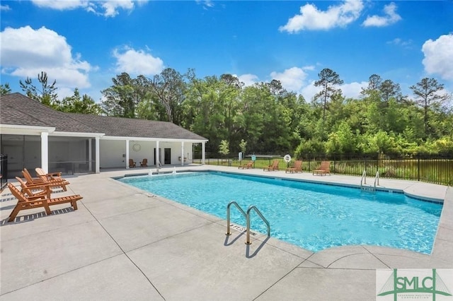 pool with a patio area and fence