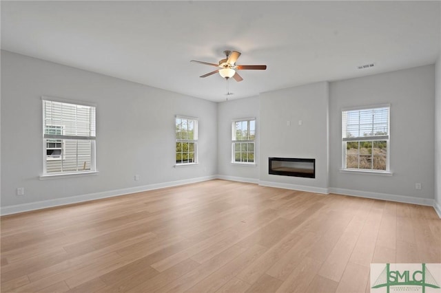 unfurnished living room with light wood-style floors, ceiling fan, visible vents, and plenty of natural light
