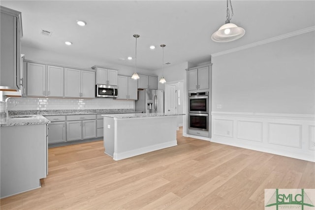 kitchen featuring stainless steel appliances, light wood-type flooring, a sink, and gray cabinets