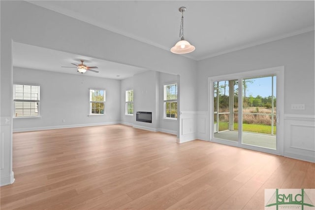 unfurnished living room featuring light wood-style flooring, ceiling fan, plenty of natural light, and a glass covered fireplace
