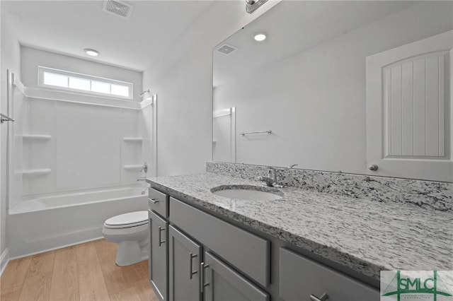 full bath with vanity, visible vents, toilet, wood finished floors, and washtub / shower combination
