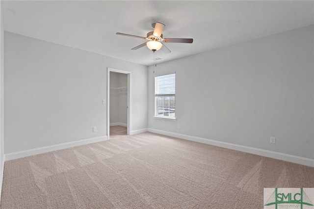 unfurnished bedroom with a closet, baseboards, carpet flooring, a ceiling fan, and a walk in closet