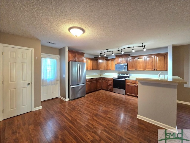 kitchen with visible vents, light countertops, a peninsula, dark wood finished floors, and stainless steel appliances
