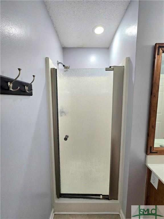 bathroom with a textured ceiling and a stall shower