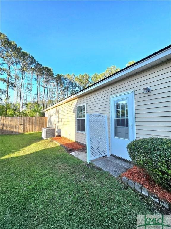 view of yard featuring fence and central AC