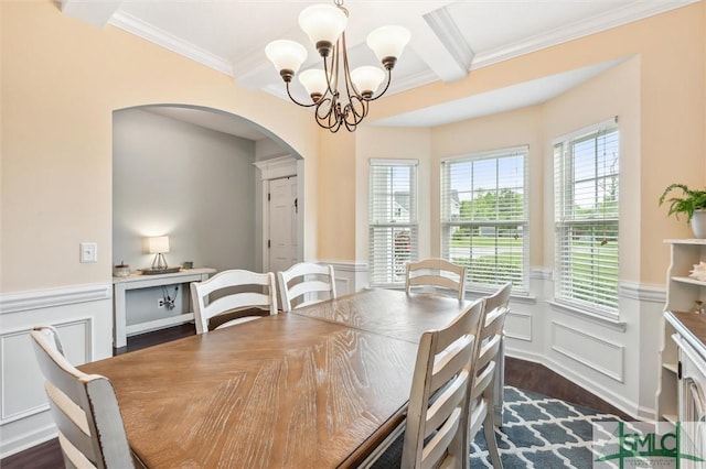 dining space featuring arched walkways, an inviting chandelier, a decorative wall, dark wood-style flooring, and crown molding