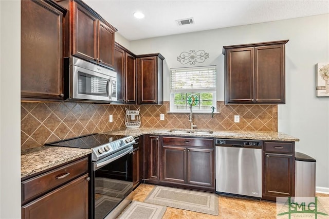 kitchen with light stone countertops, dark brown cabinetry, visible vents, and appliances with stainless steel finishes