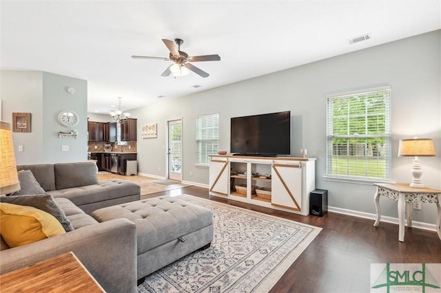 living room with ceiling fan with notable chandelier, wood finished floors, baseboards, and visible vents