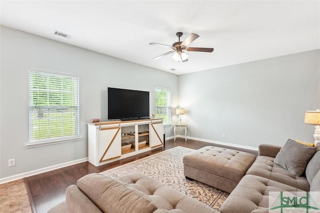 living area with dark wood finished floors, visible vents, baseboards, and ceiling fan
