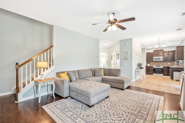 living area with arched walkways, wood finished floors, a ceiling fan, and stairs