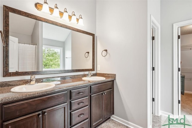 full bathroom with double vanity, baseboards, and a sink