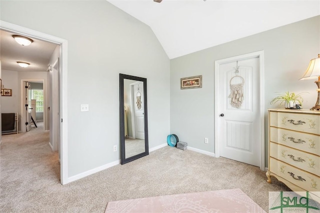 interior space featuring light carpet, baseboards, and vaulted ceiling