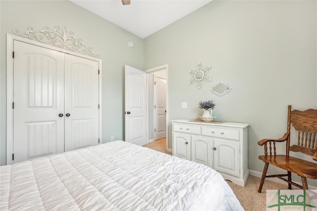 bedroom featuring a closet, light colored carpet, baseboards, and a ceiling fan