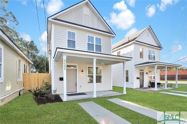 view of front of home featuring board and batten siding, covered porch, a front yard, and fence