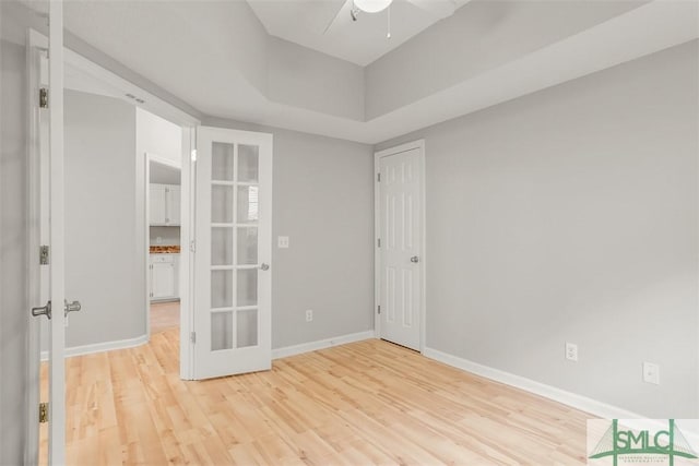 spare room with light wood-type flooring, french doors, ceiling fan, and baseboards