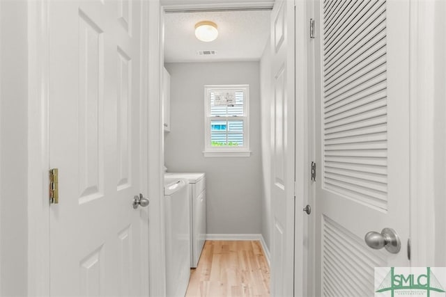 laundry area featuring a textured ceiling, light wood-type flooring, visible vents, washing machine and dryer, and cabinet space