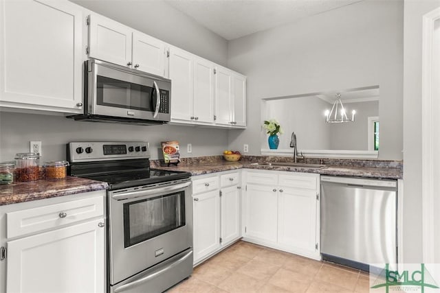 kitchen featuring white cabinets, a notable chandelier, a sink, appliances with stainless steel finishes, and dark stone counters