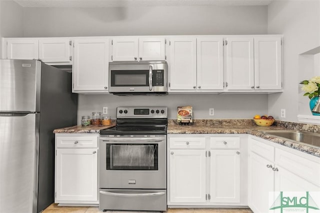 kitchen featuring stone countertops, a sink, white cabinetry, and stainless steel appliances