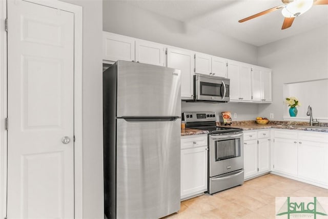 kitchen featuring appliances with stainless steel finishes, stone counters, a sink, and white cabinetry