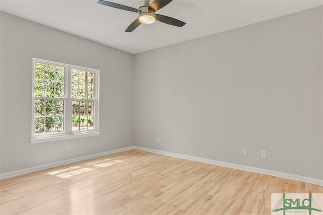 empty room featuring light wood finished floors, baseboards, and a ceiling fan