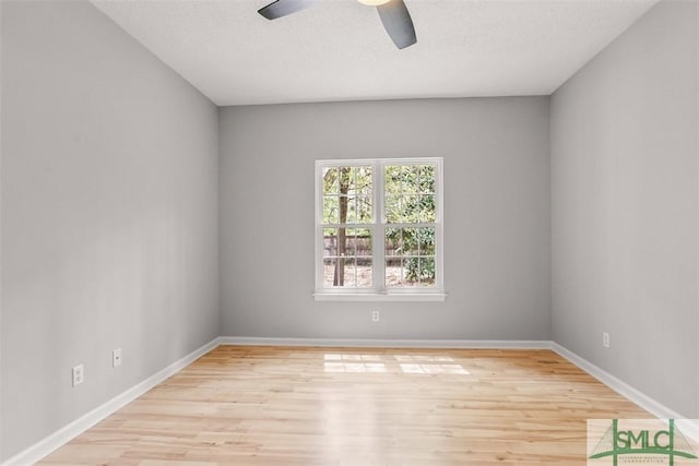 spare room featuring a textured ceiling, baseboards, light wood finished floors, and a ceiling fan