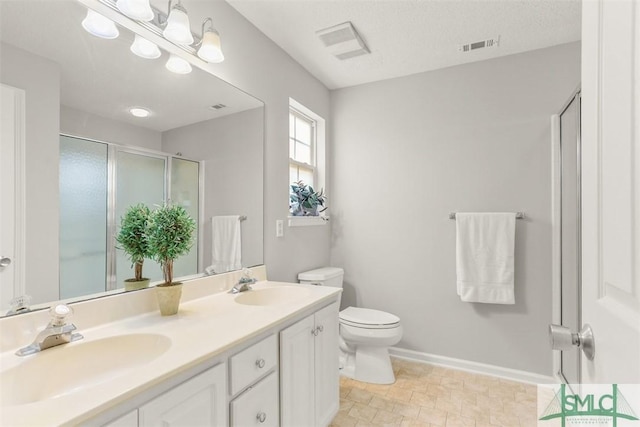 bathroom featuring a sink, toilet, a shower stall, and double vanity