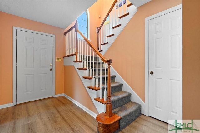 entrance foyer featuring baseboards, wood finished floors, and stairs
