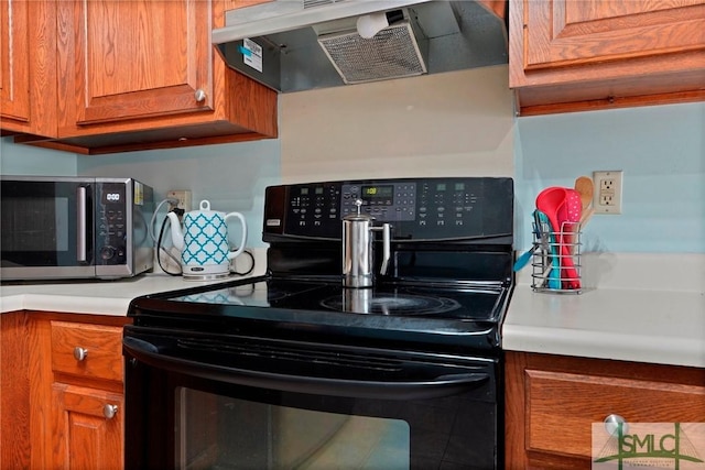 kitchen featuring stainless steel microwave, mail area, extractor fan, brown cabinetry, and black range with electric stovetop