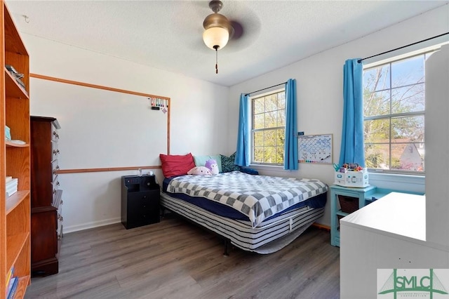 bedroom with a textured ceiling, wood finished floors, ceiling fan, and baseboards