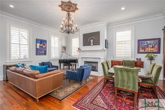 living area featuring a chandelier, crown molding, recessed lighting, wood finished floors, and a premium fireplace