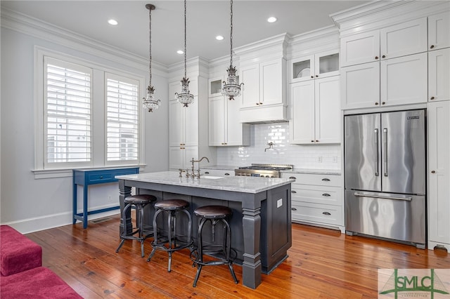 kitchen featuring stove, tasteful backsplash, ornamental molding, a sink, and high end fridge