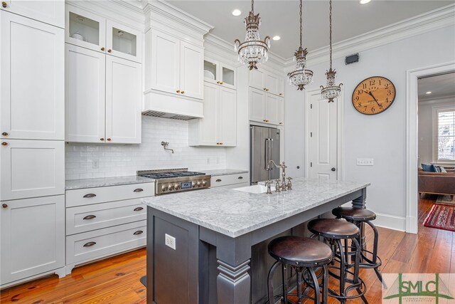 kitchen featuring a breakfast bar, an inviting chandelier, crown molding, stainless steel appliances, and light wood finished floors