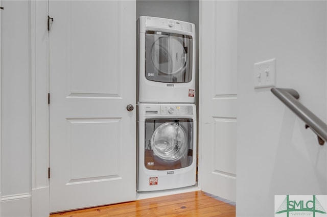 washroom with stacked washer and dryer, laundry area, and wood finished floors