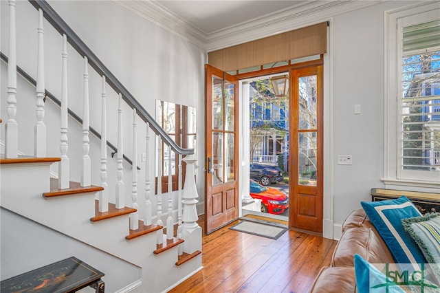 entryway featuring plenty of natural light, stairway, light wood-style flooring, and ornamental molding