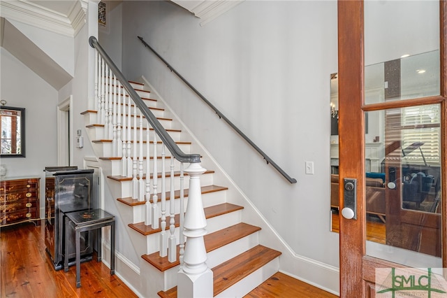 stairway with baseboards, ornamental molding, and wood finished floors