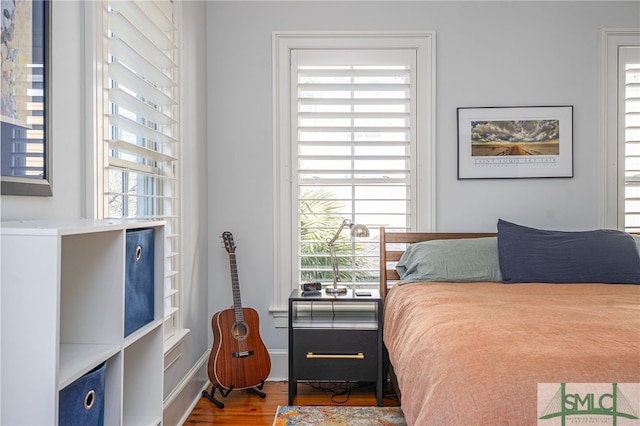 bedroom with wood finished floors and multiple windows