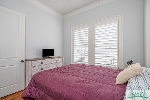 bedroom with crown molding and wood finished floors