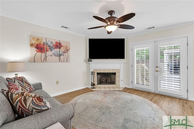 living area with crown molding, visible vents, and wood finished floors