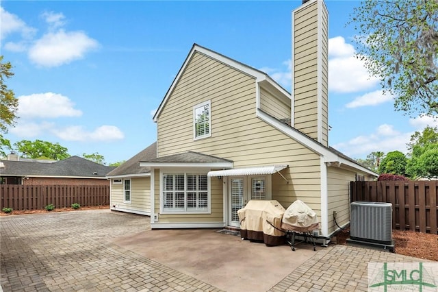 back of property featuring a chimney, a patio area, fence, and central AC
