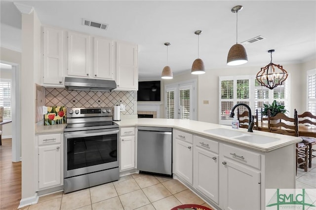 kitchen with appliances with stainless steel finishes, a sink, visible vents, and under cabinet range hood