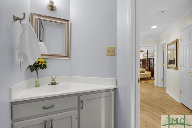 bathroom with baseboards, recessed lighting, vanity, and wood finished floors