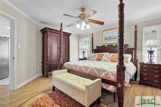 bedroom featuring multiple windows, ornamental molding, and stainless steel fridge