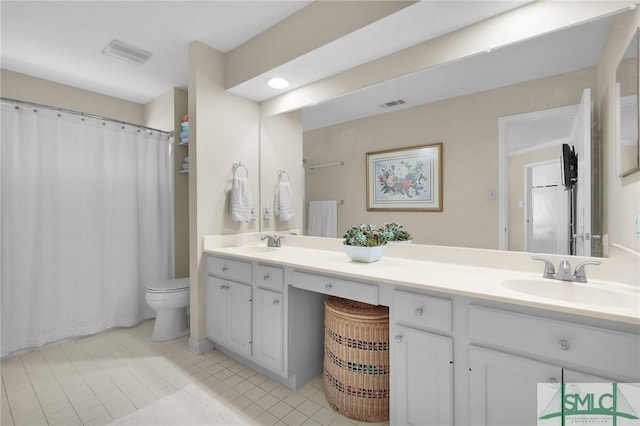 bathroom with a sink, visible vents, toilet, and double vanity